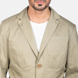 A well-dressed man in a beige cotton blazer jacket, radiating elegance and charm.