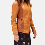 A woman in a leather brown jacket and floral skirt, looking stylish and confident.
